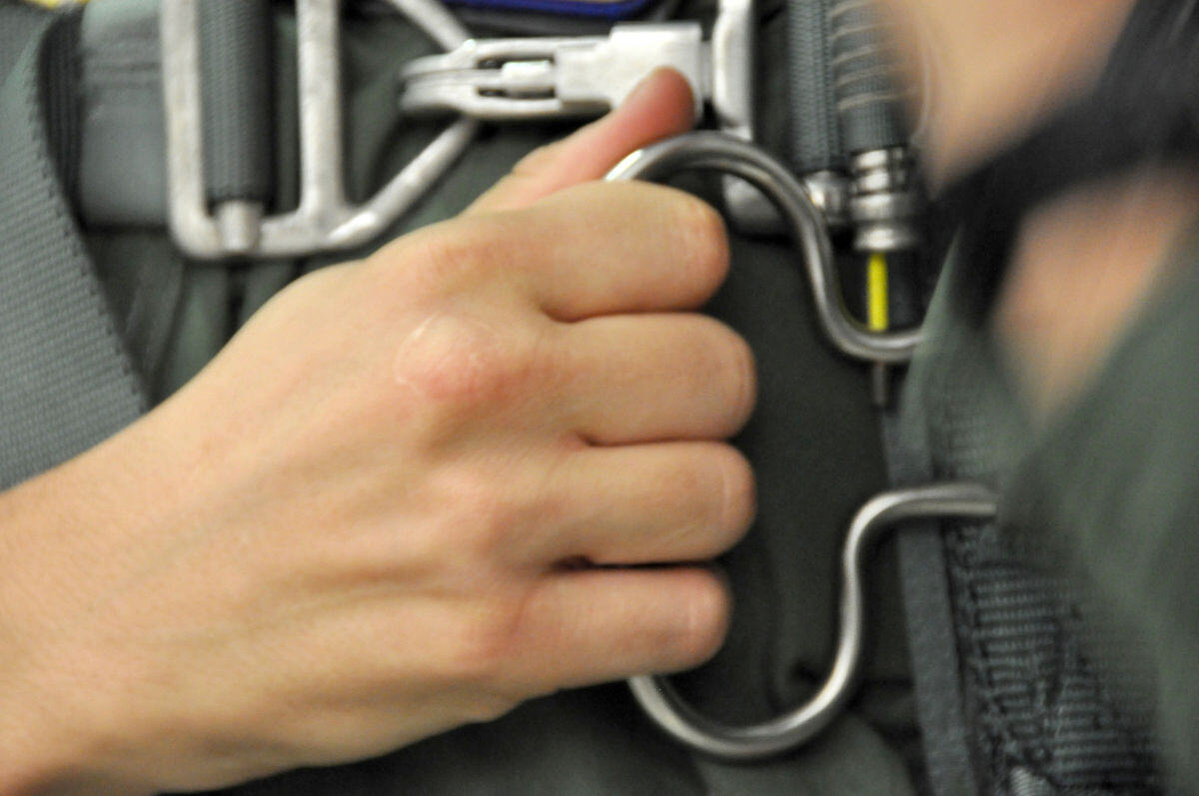Parachute ripcord being pulled by someone's hand.